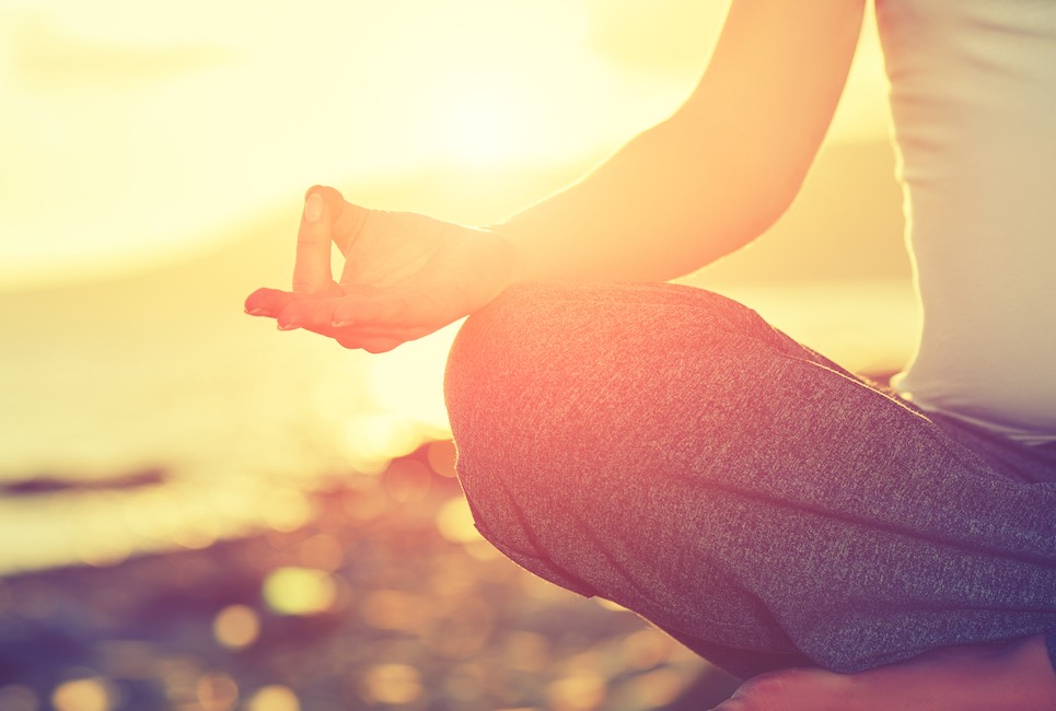 Yoga concept. hand woman practicing lotus pose on the beach at sunset